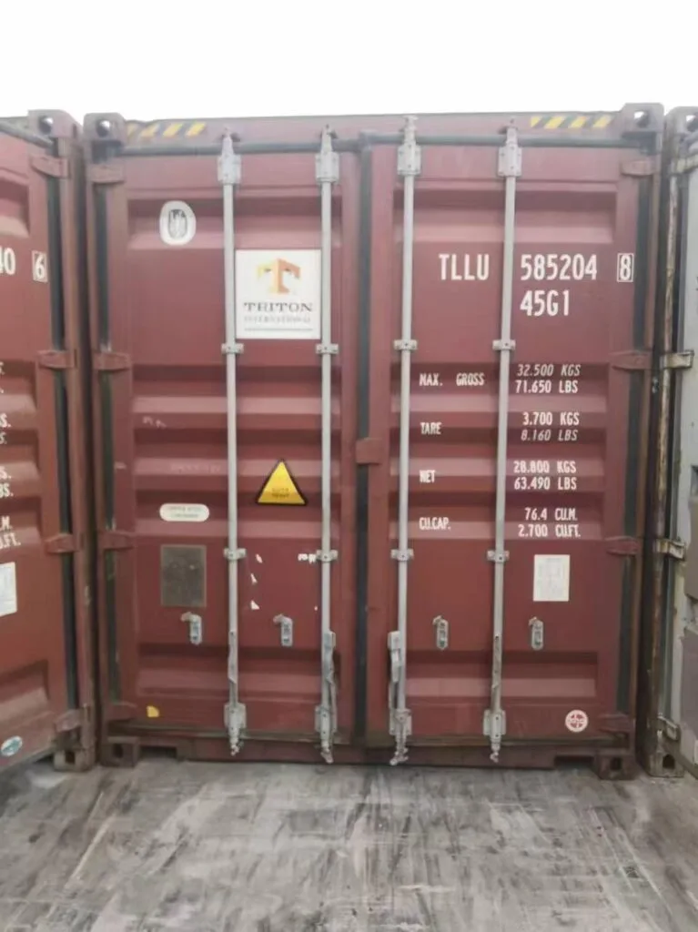 Rear view of a red 40-foot Triton shipping container (ID: TLLU 585204) inside a cargo hold, ready for international transport.